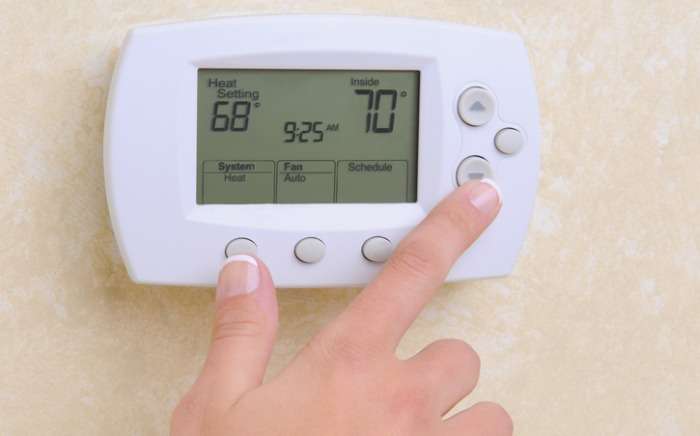 closeup of hand and thermostat picture id530325621 1