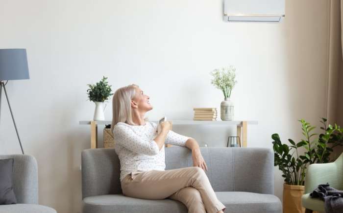middle aged woman switching on air conditioner in living room picture id1188934085 1