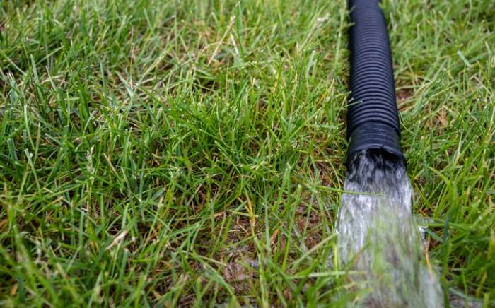 residential sump pump discharging water from the end of a flexible picture id1169475841 1