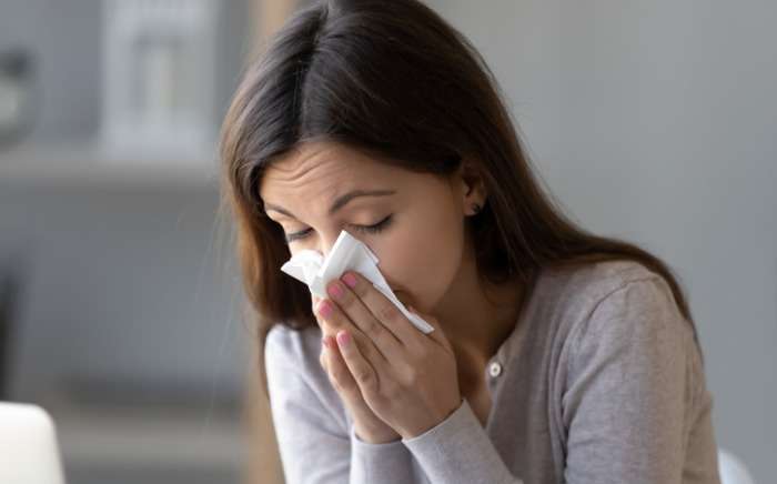 sick young woman holding tissue and blowing her running nose picture id1150540167 1