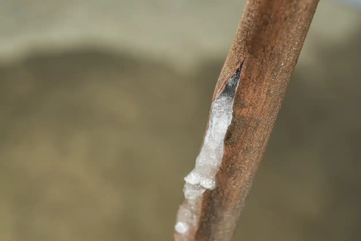 An image of a copper pipe that has burst, but the water has frozen.