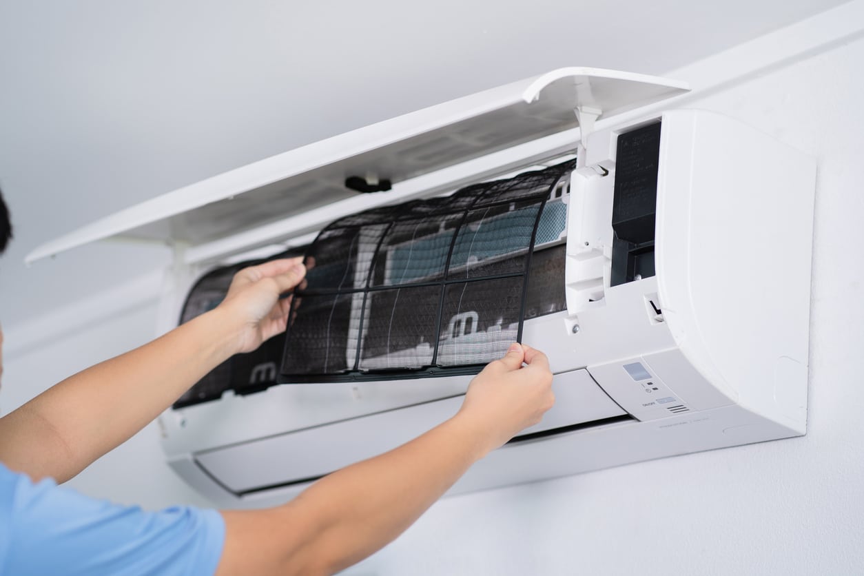An image of a technician performing filter maintenance on a trans-wall AC unit.