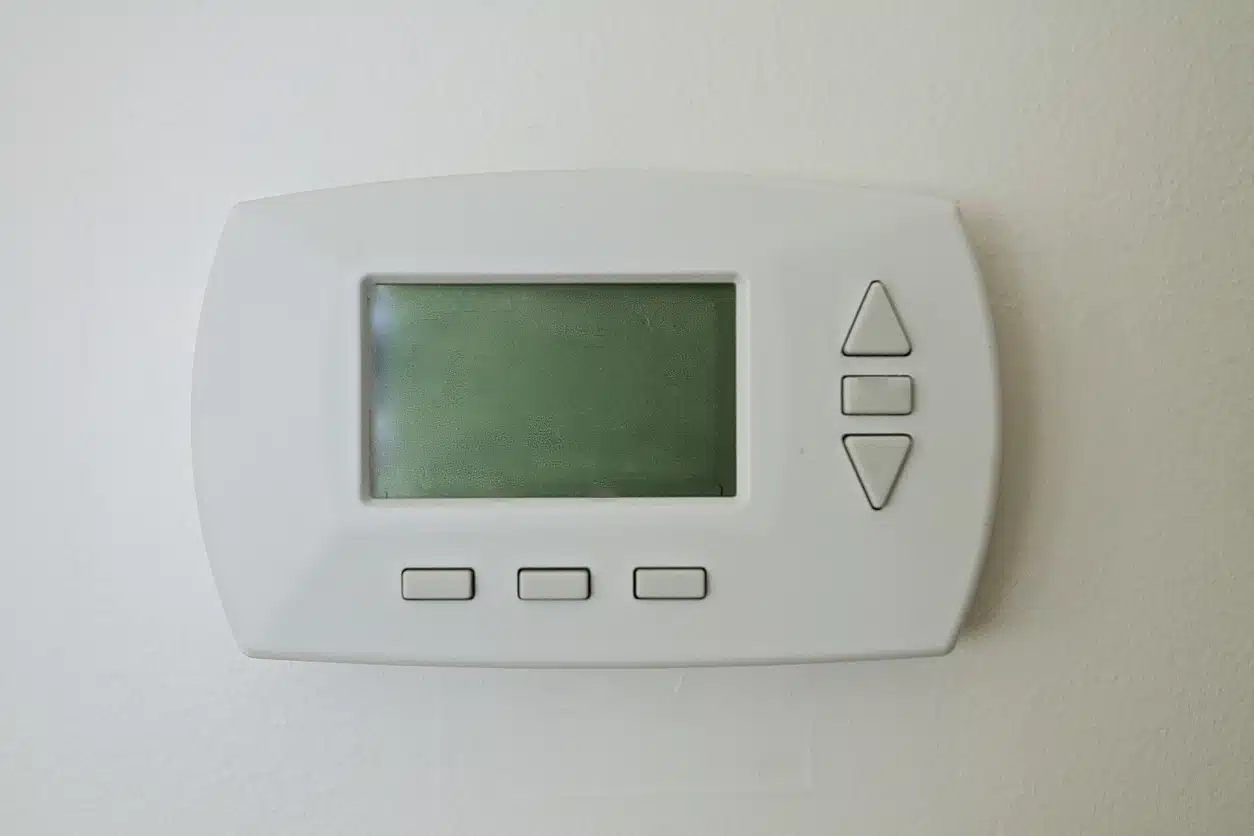 A blank, programmable thermostat mounted on a wall.